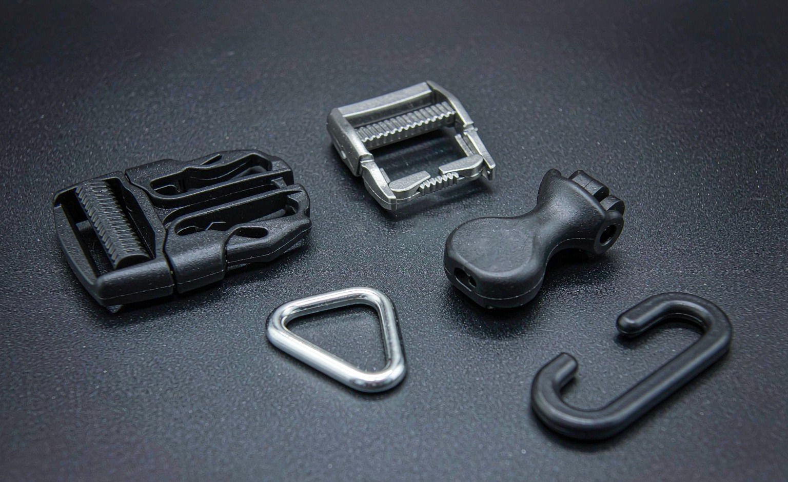 Macro view of backpack hardware: side-release buckle, ladder lock, cord lock, D-ring and G-hook