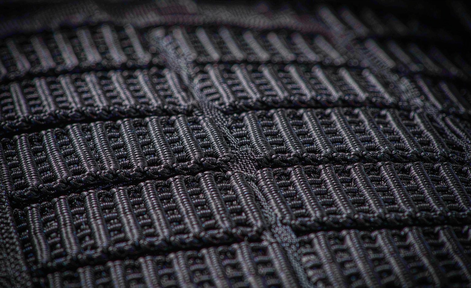 Macro view of MOLLE PALS webbing rows with a pouch strap threaded through a channel