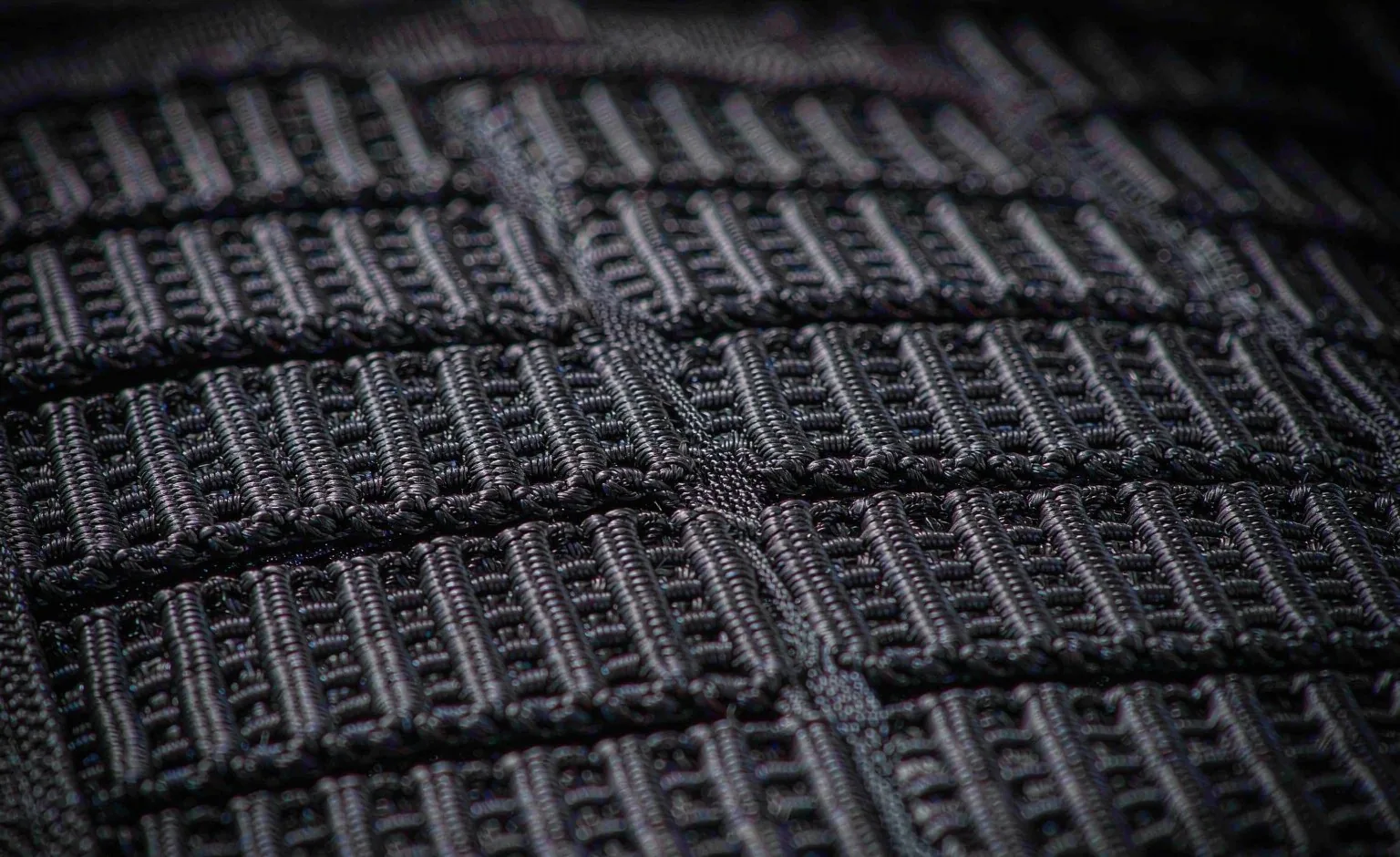 Close-up of a MOLLE attachment grid showing webbing channels and channel spacing