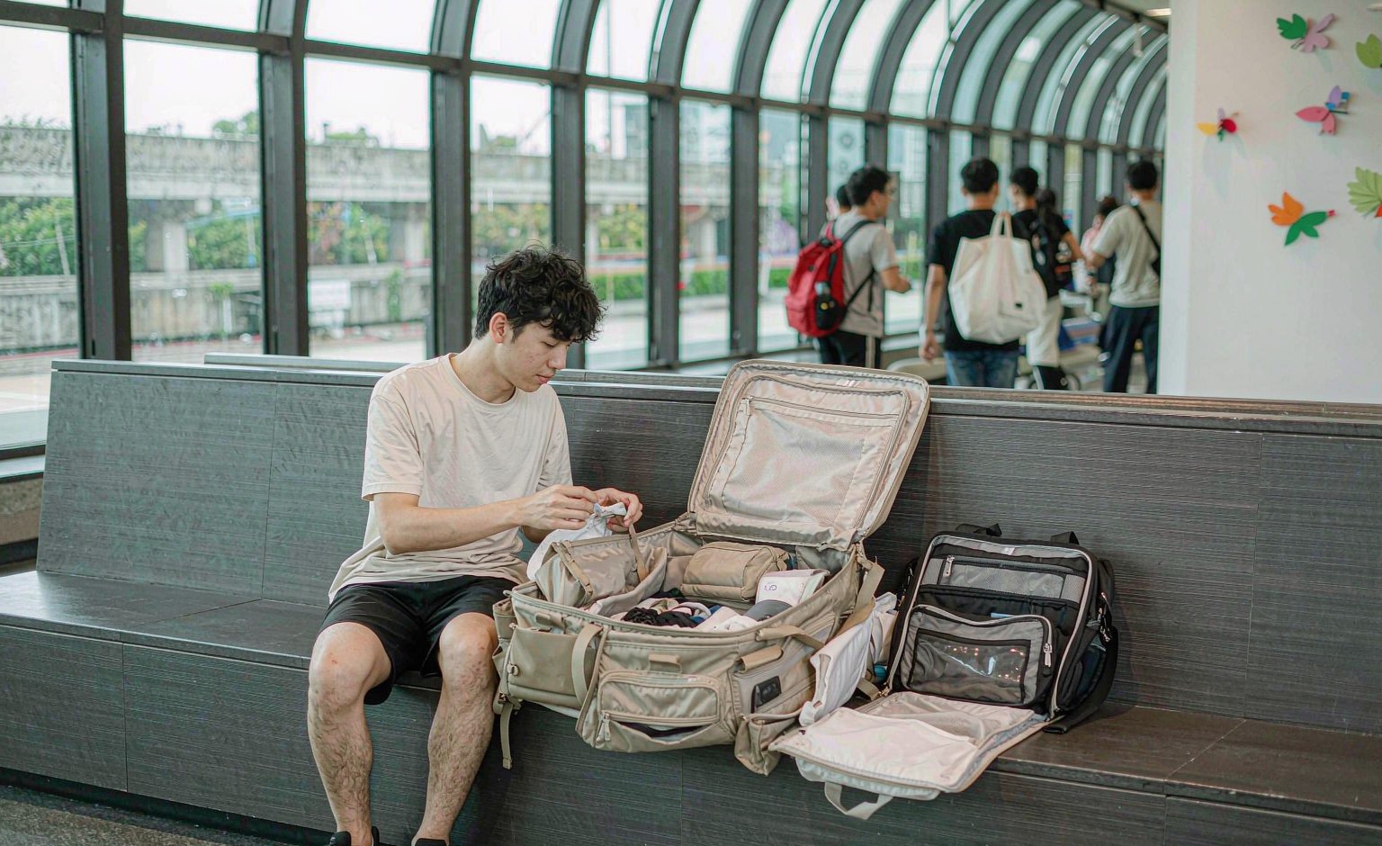 Traveller in a terminal with a convertible carry-on backpack opened flat beside packing cubes